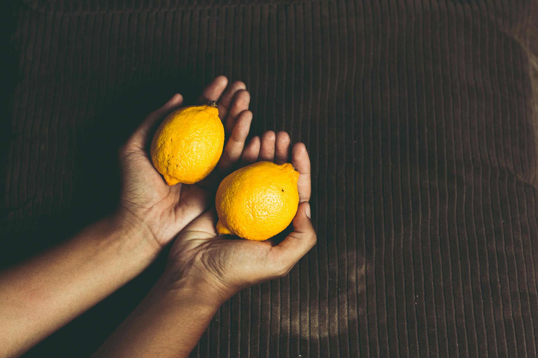 Close-up of fresh lemons held in cupped hands, symbolizing the gentle touch of lemon vibrators.